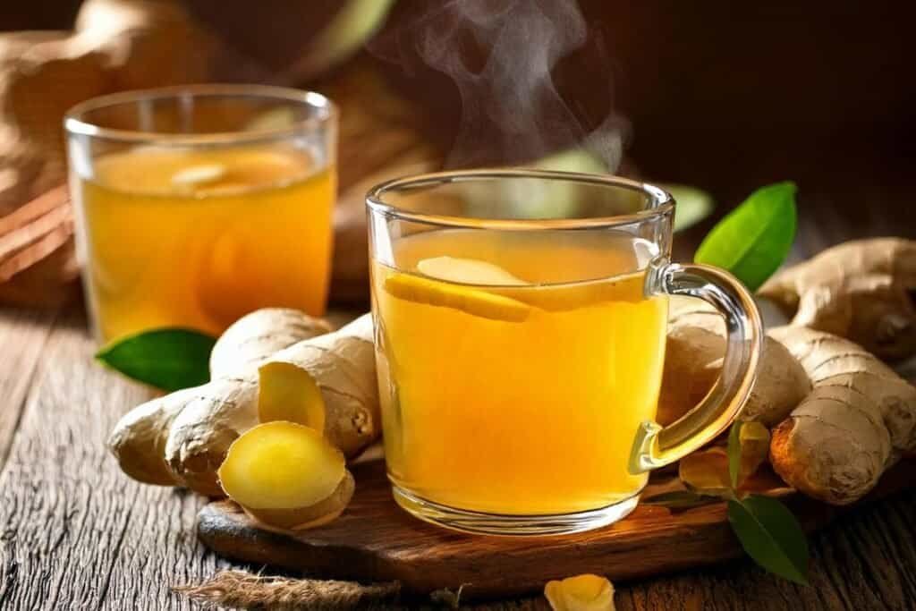 Warm ginger tea with fresh ginger root on a rustic wooden table, evoking holistic wellness and traditional healing practices. a great addition to a turmeric spice recipe.