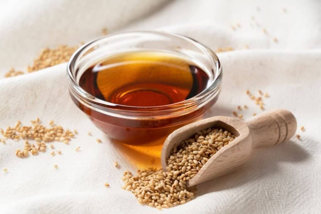Sesame seeds and a bowl of sesame oil on a white cloth, promoting wellness and holistic health.